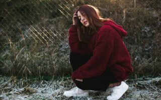 selective focus photography of woman half-sitting near fence