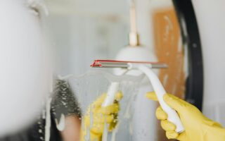 Faceless person removing water from mirror