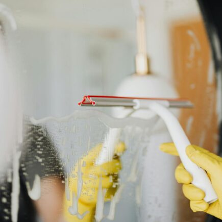 Faceless person removing water from mirror