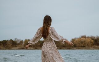 woman in white dress standing on sea shore during daytime