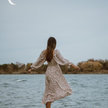 woman in white dress standing on sea shore during daytime