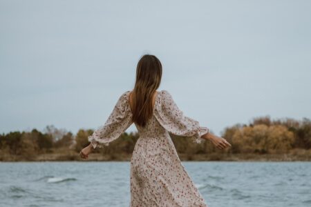 woman in white dress standing on sea shore during daytime